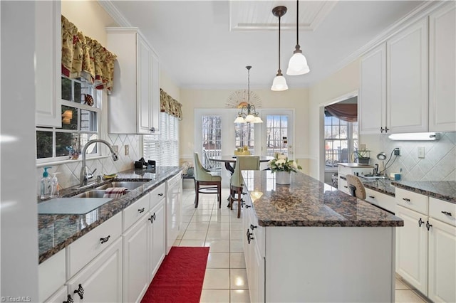 kitchen with white cabinetry, white dishwasher, sink, and a kitchen island