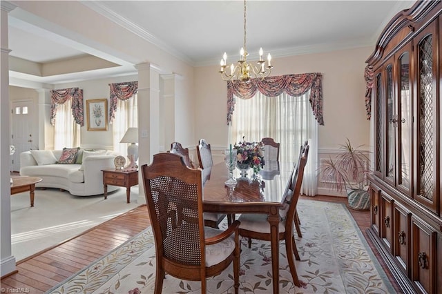 dining area with ornamental molding, light hardwood / wood-style floors, a chandelier, and ornate columns