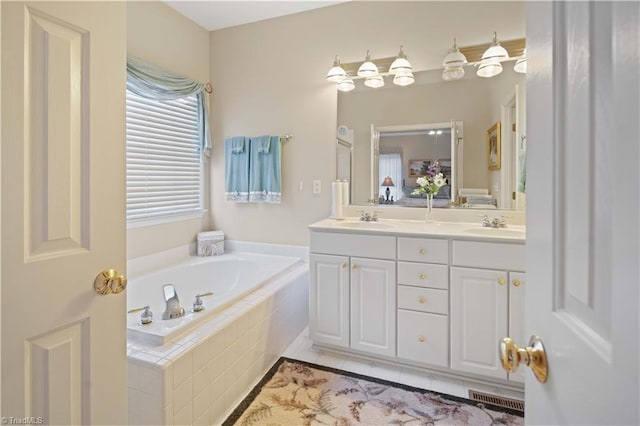 bathroom with vanity, tile patterned flooring, and tiled bath