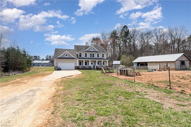 view of front facade with fence, concrete driveway, a front yard, an outbuilding, and an attached garage