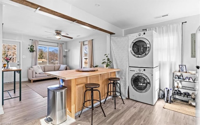 clothes washing area with light hardwood / wood-style flooring, stacked washer / dryer, and ceiling fan