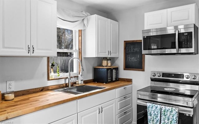 kitchen with wood counters, sink, white cabinetry, and stainless steel appliances