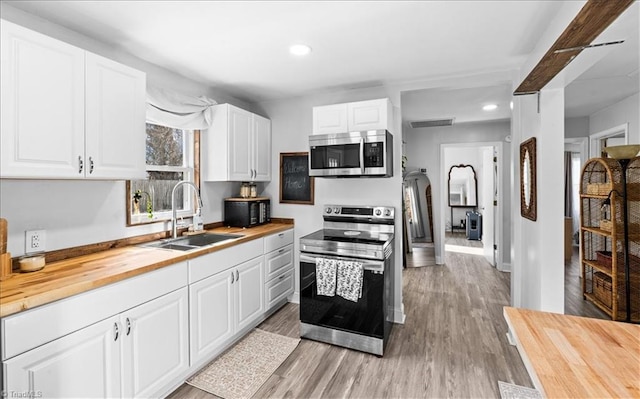 kitchen featuring wood counters, stainless steel appliances, sink, light hardwood / wood-style flooring, and white cabinetry