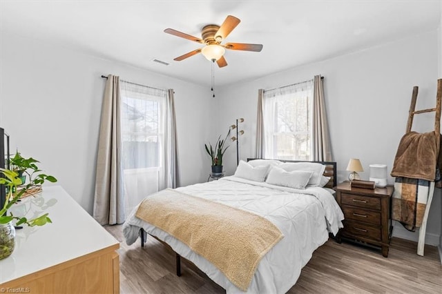 bedroom with multiple windows, ceiling fan, and hardwood / wood-style flooring