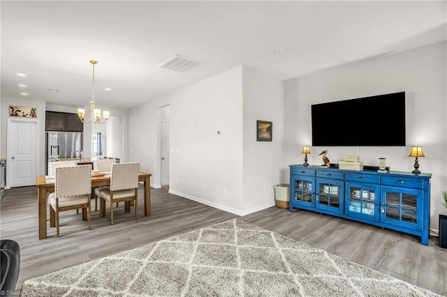 dining space featuring baseboards, an inviting chandelier, visible vents, and light wood-style floors