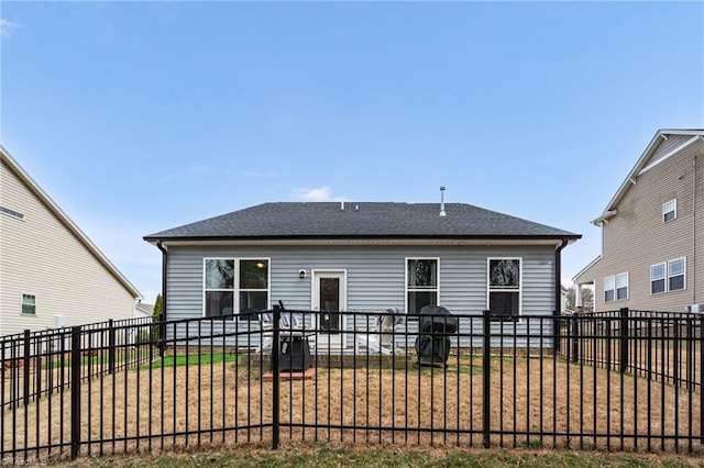 rear view of house featuring a fenced backyard and a shingled roof