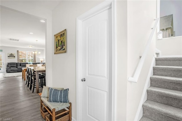 staircase featuring baseboards, visible vents, wood finished floors, an inviting chandelier, and recessed lighting