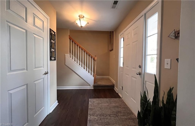 foyer with stairs, dark wood-style floors, visible vents, and baseboards