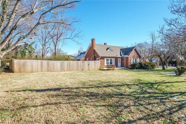 exterior space featuring a yard, brick siding, fence, and a chimney