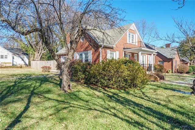 view of front of property featuring brick siding, a front lawn, and fence