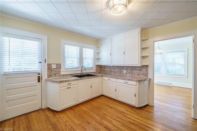 kitchen with visible vents, white cabinets, light wood-style flooring, open shelves, and a sink