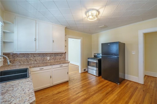 kitchen with a sink, white cabinetry, freestanding refrigerator, stainless steel electric range oven, and open shelves