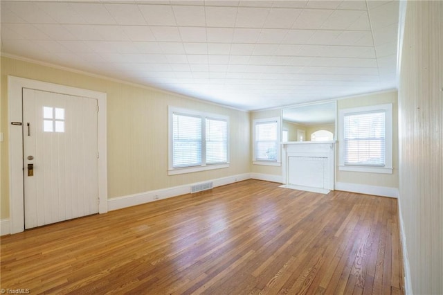 unfurnished living room with ornamental molding, visible vents, plenty of natural light, and hardwood / wood-style flooring