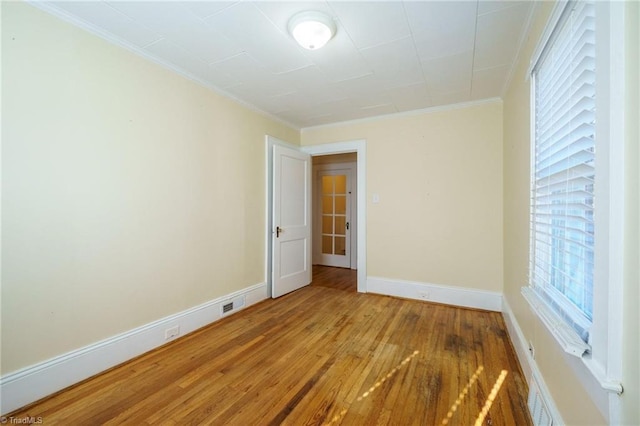 spare room with crown molding, baseboards, and wood finished floors