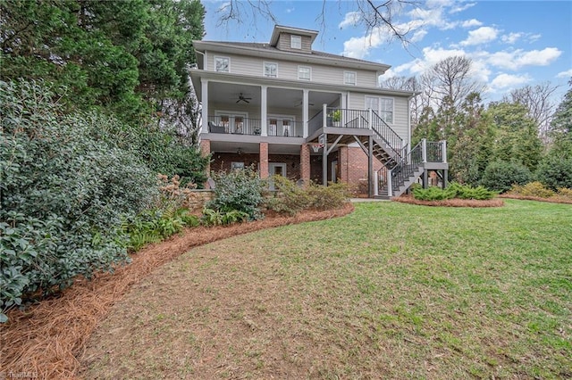 back of property with brick siding, stairway, ceiling fan, and a yard