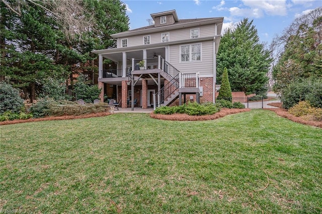 rear view of property with a lawn, a patio, fence, brick siding, and stairs