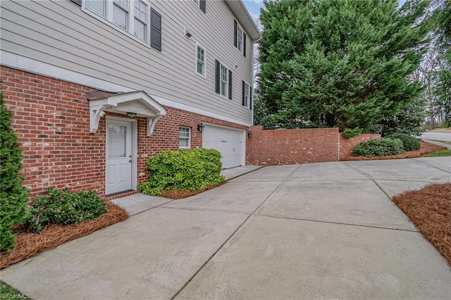 view of side of home featuring a garage, brick siding, and concrete driveway