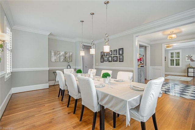 dining room with crown molding, light wood-style flooring, and baseboards