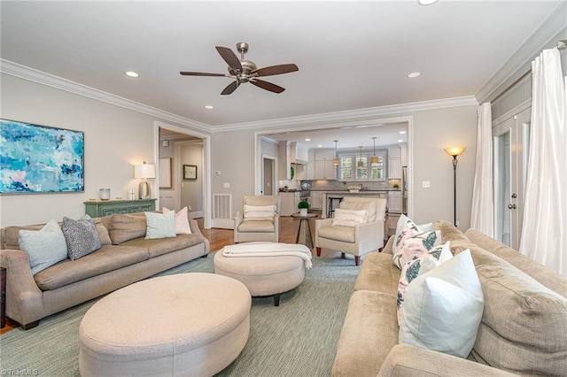 living room featuring visible vents, crown molding, baseboards, recessed lighting, and light wood-style flooring