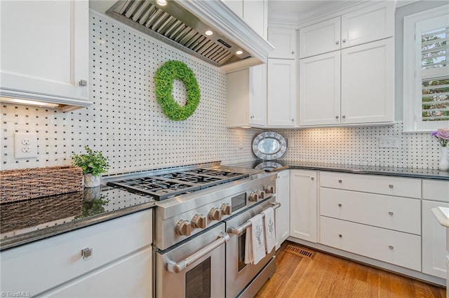 kitchen featuring dark stone countertops, double oven range, white cabinetry, and premium range hood