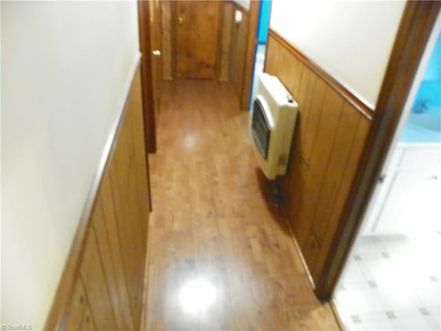 hallway featuring wood walls, light hardwood / wood-style flooring, and heating unit