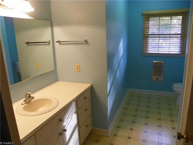 bathroom featuring vanity, heating unit, and toilet