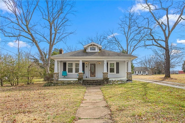 bungalow featuring a porch, a chimney, and a front yard