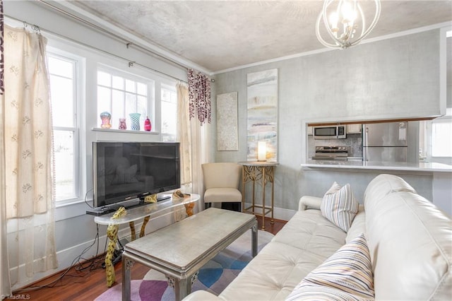 living room featuring ornamental molding, an inviting chandelier, baseboards, and wood finished floors