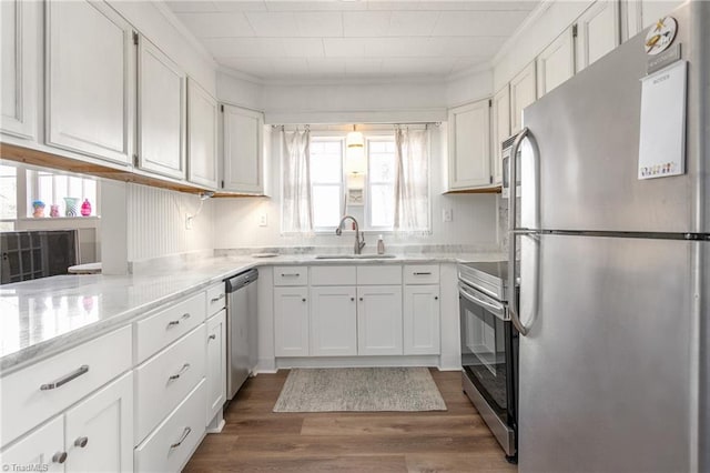 kitchen featuring dark wood-style floors, stainless steel appliances, light countertops, white cabinetry, and a sink