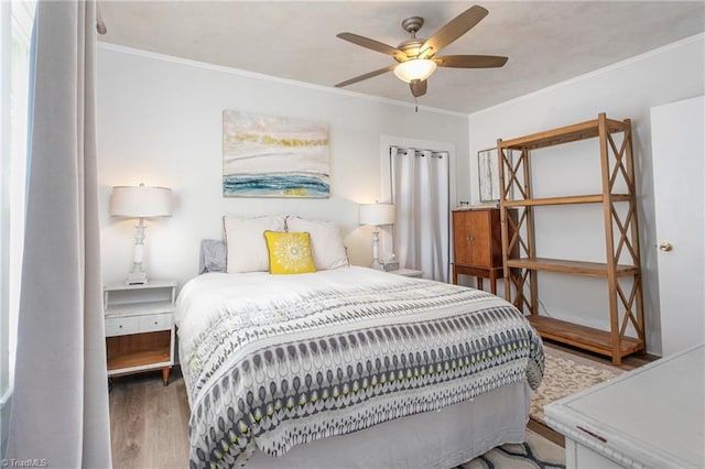 bedroom with ceiling fan, wood finished floors, and crown molding