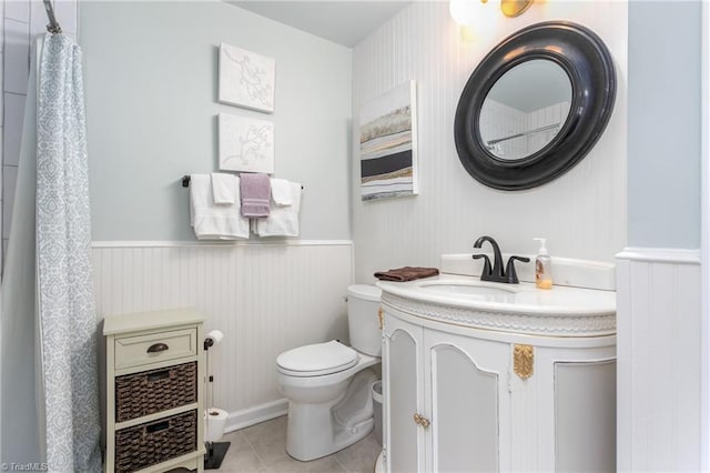 full bath with toilet, a wainscoted wall, vanity, and tile patterned floors