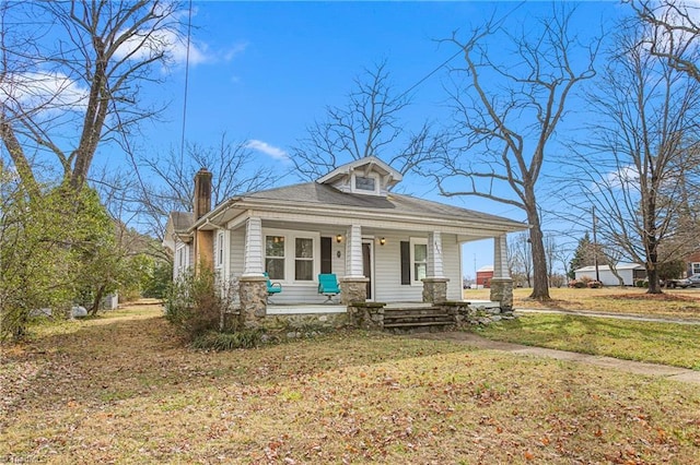 view of front of home with a porch, a front lawn, and a chimney