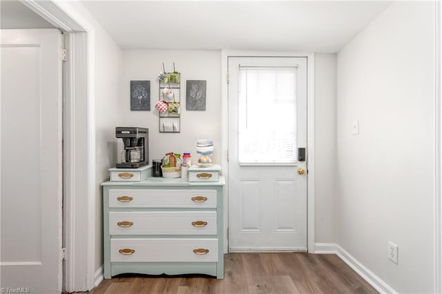 doorway to outside featuring baseboards and wood finished floors