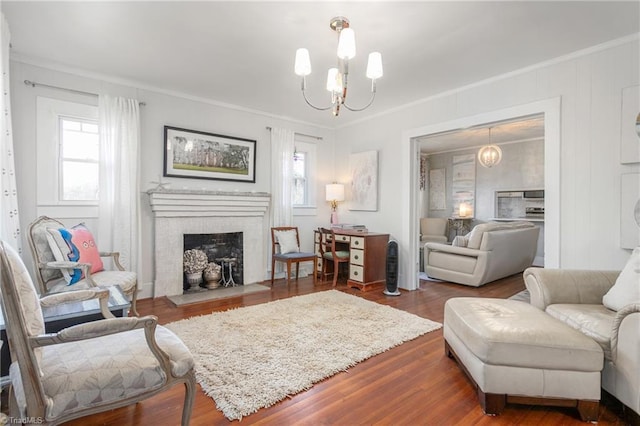 living area with dark wood-style floors, a fireplace with flush hearth, ornamental molding, and an inviting chandelier