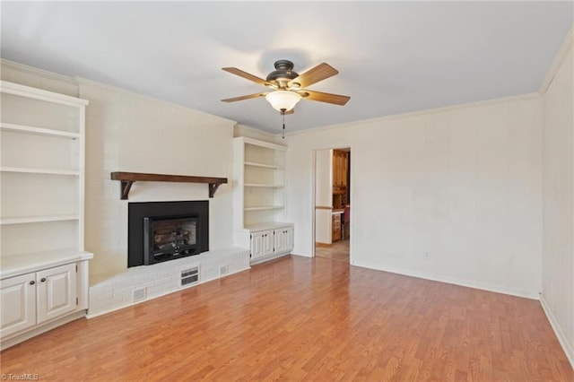 unfurnished living room featuring ceiling fan, crown molding, light wood-type flooring, and a fireplace