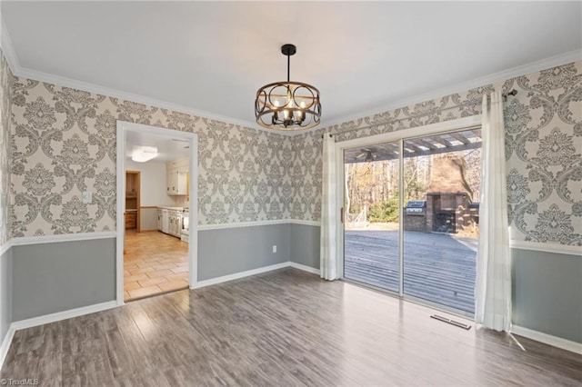 unfurnished dining area with crown molding, wood-type flooring, and a notable chandelier