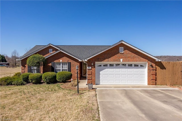 ranch-style house with fence, concrete driveway, a front yard, an attached garage, and brick siding