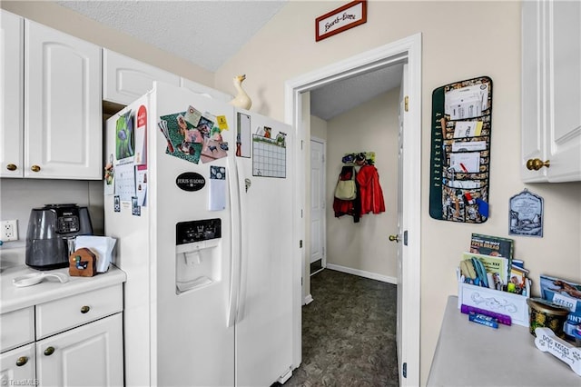 kitchen with white cabinets, white refrigerator with ice dispenser, light countertops, and baseboards