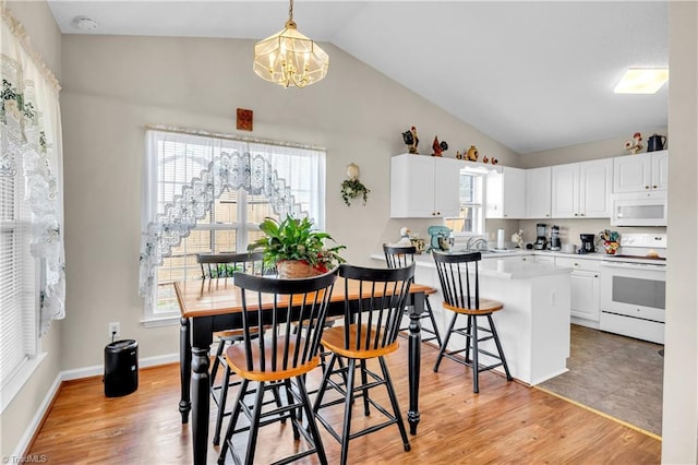 kitchen with a wealth of natural light, white cabinetry, white appliances, light wood finished floors, and lofted ceiling