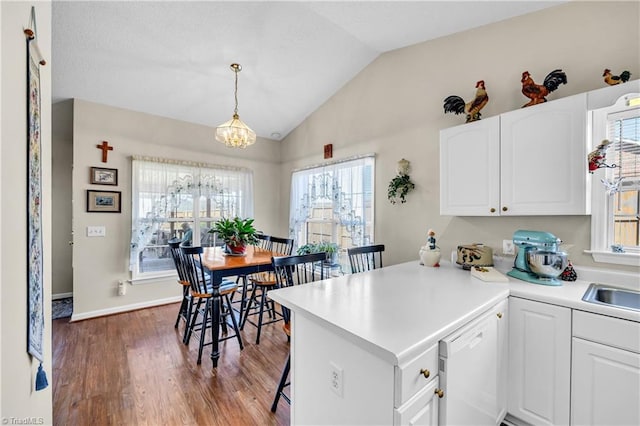 kitchen featuring lofted ceiling, white cabinets, wood finished floors, and a peninsula