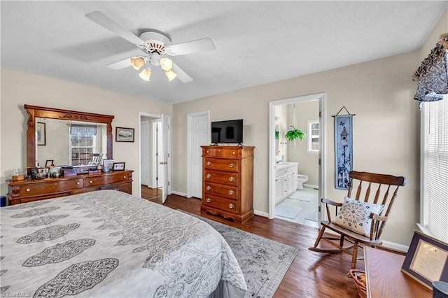 bedroom featuring dark wood-type flooring, multiple windows, baseboards, and ensuite bathroom