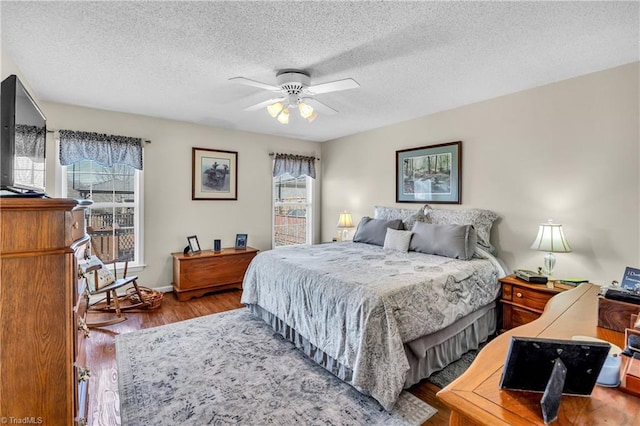 bedroom with baseboards, a textured ceiling, a ceiling fan, and wood finished floors