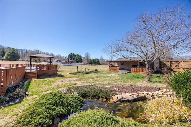 view of yard with a gazebo, a wooden deck, and fence