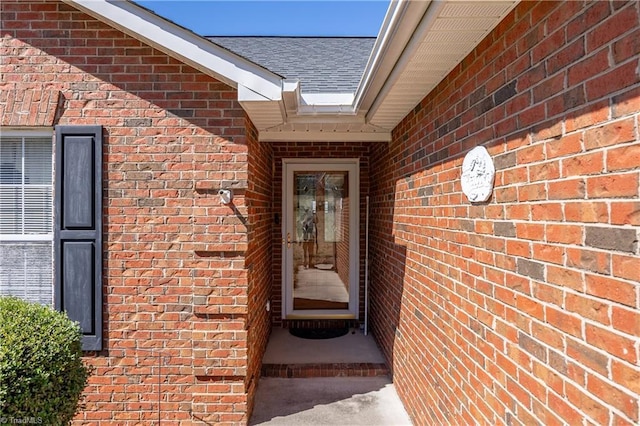 property entrance with brick siding and a shingled roof