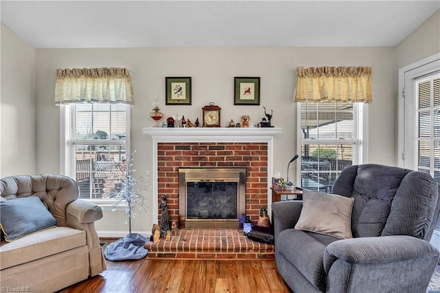 living area featuring a brick fireplace, wood finished floors, and baseboards