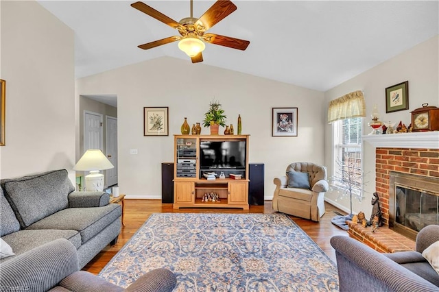 living area featuring ceiling fan, baseboards, lofted ceiling, a fireplace, and wood finished floors