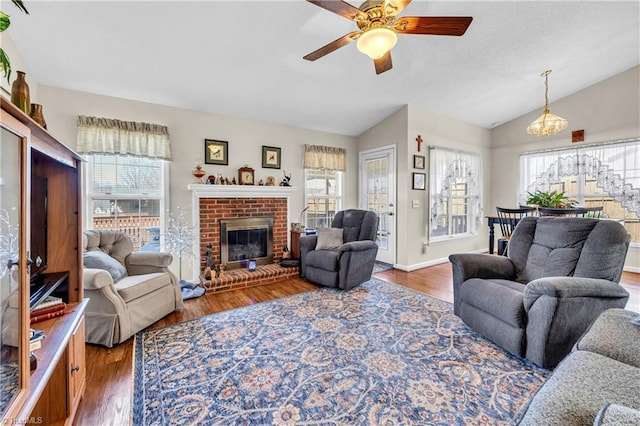 living area featuring lofted ceiling, a healthy amount of sunlight, wood finished floors, and a fireplace