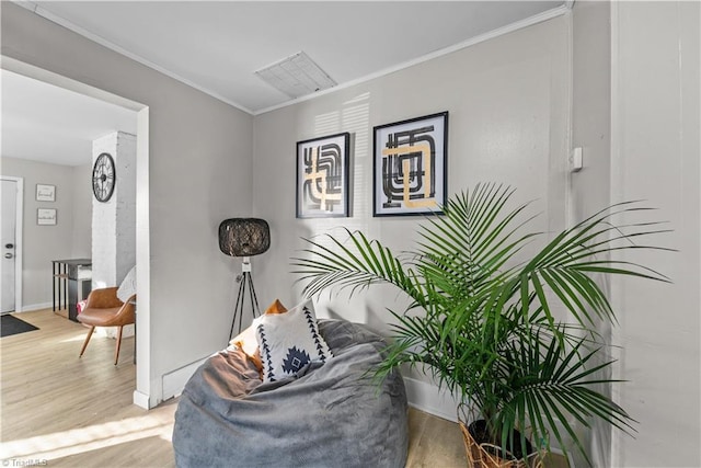 sitting room with hardwood / wood-style flooring and crown molding