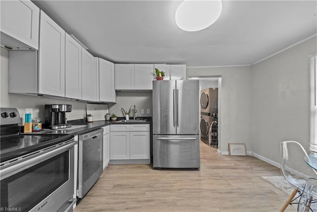 kitchen featuring sink, stainless steel appliances, stacked washer / dryer, light hardwood / wood-style floors, and white cabinets