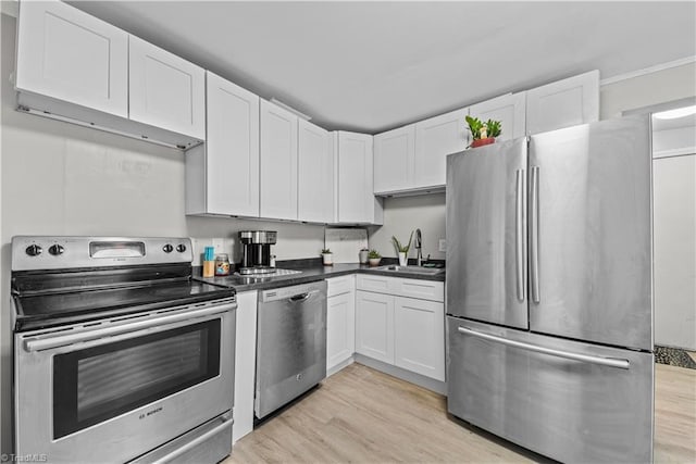 kitchen featuring appliances with stainless steel finishes, sink, white cabinets, and light wood-type flooring